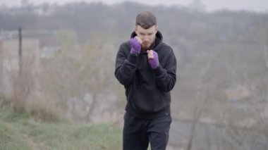 Erkek boksör şehirde spor eğitimi alıyor, ağır çekimde.