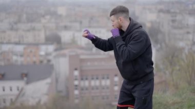 Erkek boksör şehirde spor eğitimi alıyor, ağır çekimde.