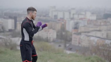 Erkek boksör şehirde spor eğitimi alıyor, ağır çekimde.