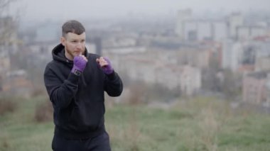 Erkek boksör şehirde spor eğitimi alıyor, ağır çekimde.