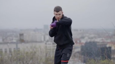 Erkek boksör şehirde spor eğitimi alıyor, ağır çekimde.