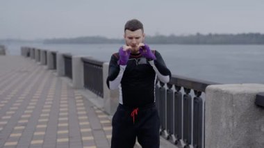 Erkek boksör şehirde spor eğitimi alıyor, ağır çekimde.