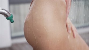 Kadın dışarıda duş alıyor, ağır çekimde.