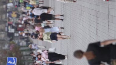 KYIV, UKRAINE - 30 AĞUSTOS 2024: Yazın bir şehir caddesinde kalabalığın dikey videosu.
