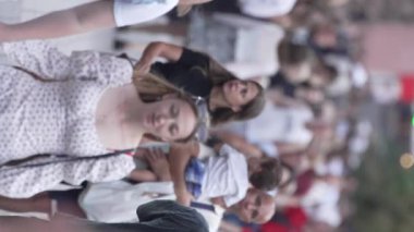 KYIV, UKRAINE 30 AĞUSTOS 2024: Yazın bir şehir caddesinde kalabalığın dikey videosu.