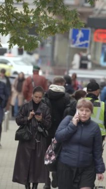 KYIV, UKRAINE - 6 Ekim 2024: Sonbaharda bir şehir caddesinde kalabalığın dikey videosu.