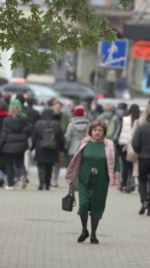 KYIV, UKRAINE - 6 Ekim 2024: Sonbaharda bir şehir caddesinde kalabalığın dikey videosu.