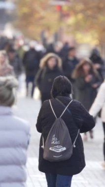 KYIV, UKRAINE ECTOBER 6, 2024: Sonbaharda cadde boyunca yürüyen insanların dikey videosu, yavaş çekim