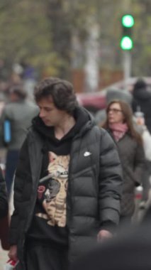 KYIV, UKRAINE ECTOBER 6, 2024: Sonbaharda cadde boyunca yürüyen insanların dikey videosu, yavaş çekim