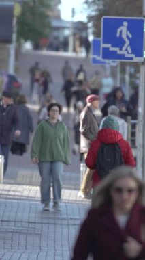 KYIV, UKRAINE ECTOBER 6, 2024: Sonbaharda cadde boyunca yürüyen insanların dikey videosu, yavaş çekim