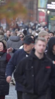 KYIV, UKRAINE - 6 Ekim 2024: Sonbaharda sokakta yürüyen insanların dikey videosu, yavaş çekim