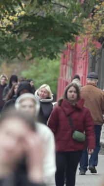 KYIV, UKRAINE - 6 Ekim 2024: Birçok insanın sonbaharda yavaş çekimde sokakta yürüdüğü dikey video