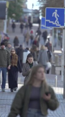 KYIV, UKRAINE - 6 Ekim 2024: Sonbaharda sokakta yürüyen insanların dikey videosu, yavaş çekim