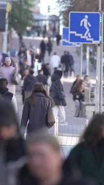 KYIV, UKRAINE - 6 Ekim 2024: Sonbaharda sokakta yürüyen insanların dikey videosu, yavaş çekim