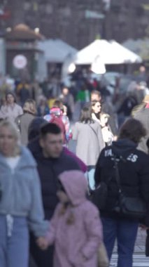 KYIV, UKRAINE - 6 Ekim 2024: Sonbaharda sokakta yürüyen insanların dikey videosu, yavaş çekim