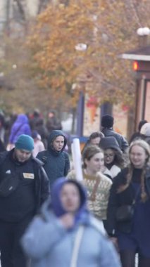 KYIV, UKRAINE - 6 Ekim 2024: Sonbaharda sokakta yürüyen insanların dikey videosu, yavaş çekim