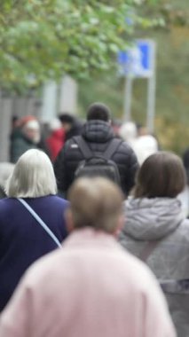 KYIV, UKRAINE - 6 Ekim 2024: Sonbaharda insanlarla dolu bir şehir sokağının dikey videosu, yavaş çekim