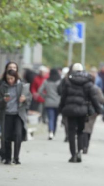 KYIV, UKRAINE - 6 Ekim 2024: Birçok insanın sonbaharda yavaş çekimde sokakta yürüdüğü dikey video