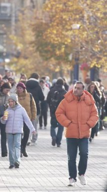 KYIV, UKRAINE - 6 Ekim 2024: Sonbaharda insanlarla dolu bir şehir sokağının dikey videosu, yavaş çekim
