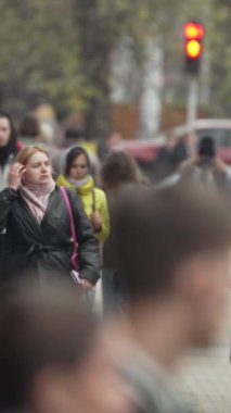 KYIV, UKRAINE - 6 Ekim 2024: Sonbaharda insanlarla dolu bir şehir sokağının dikey videosu, yavaş çekim