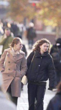 KYIV, UKRAINE - 6 Ekim 2024: Sonbaharda insanlarla dolu bir şehir sokağının dikey videosu, yavaş çekim