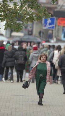 KYIV, UKRAINE - 6 Ekim 2024: Sonbaharda bir şehir caddesinde kalabalığın dikey videosu.