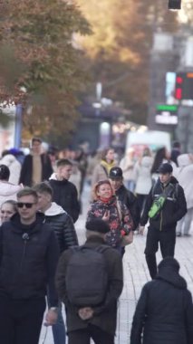 KYIV, UKRAINE - 6 Ekim 2024: Sonbaharda bir şehir caddesinde kalabalığın dikey videosu