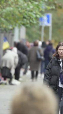 KYIV, UKRAINE - 6 Ekim 2024: Birçok insanın sonbaharda yavaş çekimde sokakta yürüdüğü dikey video