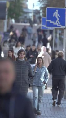 KYIV, UKRAINE - 6 Ekim 2024: Birçok insanın sonbaharda yavaş çekimde sokakta yürüdüğü dikey video