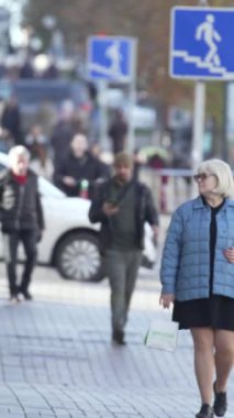 KYIV, UKRAINE - 6 Ekim 2024: Birçok insanın sonbaharda yavaş çekimde sokakta yürüdüğü dikey video