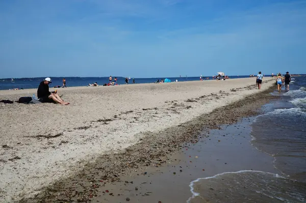 Polonya 'nın Rewa köyündeki Baltık Körfezi kıyısında tatilcilerle dolu bir sahil.           