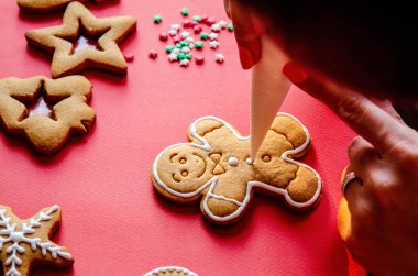 Kırmızı arka planda şekerli zencefilli kurabiye adam resmi yapma süreci. Yakın plan. Geleneksel tatil pişirme. Tatil kavramı