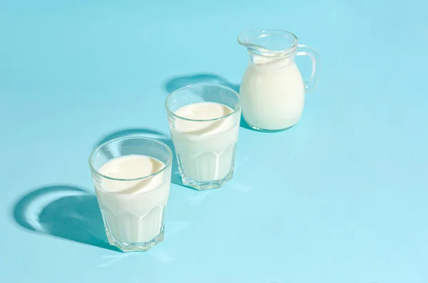 Kefir in a glass beaker on a blue background with copy space. Place for text, copy space. Hard shadows. Sour milk drink, sourdough for yeast bacterial fermentation, intestinal health concept.