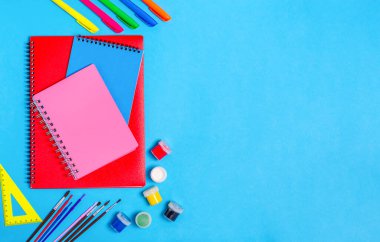 Mavi arka planda kırtasiye malzemesi olan notlar için farklı defterler. Okul hazırlığı kavramı, kırtasiye. Düz yatış, üst görünüm.