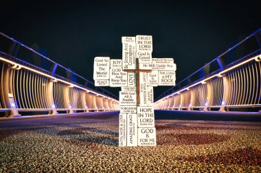 Her taşın üzerinde İncil 'in yazılı olduğu taş bloklar. Arka planda bir gece köprüsü var..