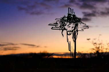 Çarmıha gerilmiş İsa Mesih 'in yüzü ve arka planda açık bir gündoğumu gökyüzü..