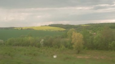 Yüksek hızlı trenin penceresinden manzarası güzel doğa manzarası vahşi arazi ve orman akşam bulutlu gökyüzü günbatımı yaz arkaplanında. Ulaşım, seyahat, demiryolu, iletişim konsepti.