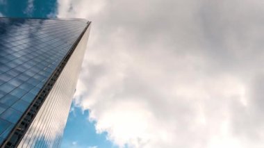 Gökyüzü arka planında Londra cam gökdeleni. Mavi gökyüzünde büyük bir bina. Büyük şehir manzarası. Güneşli bir günde hareket eden kıvırcık bulutların zamanı. Doğa, Gündüz. Meteoroloji konusu.