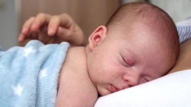annelik, çocukluk, aile, bakım, sağlık, annelik konsepti - sıcak mavi battaniyeye sarılı yeni doğmuş bebek anne göğsünün kollarında uyuyor. Anne rahatla, kucağında öpücükle kucağında bebekle evde..