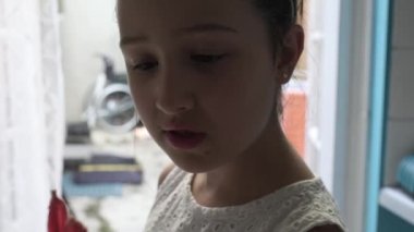 Beyaz çiçekli mutlu bir kız öğrenci. Güzel kız duygusal yüzü kapalı mekanda. Evde genç bir kız hayal et. Komik çocuk çubukta şeker yalıyor. Çocuk kameraya gülümser. Genç kız lolipop yiyor..