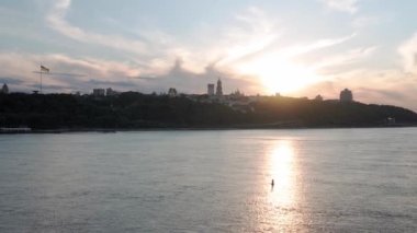 Üst hava manzaralı balıkçı teknesi okyanusu. Gün batımında Dnipro nehrinde balıkçıyla motorlu tekne gezintisi. Kiev şehrindeki Ukrayna bayrağının üzerindeki köprü manzarası. Su taşımacılığı, seyahat, yaz.