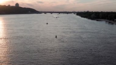 Üst hava manzaralı balıkçı teknesi okyanusu. Akşam Dnipro nehrinde gün batımında balıkçıyla motorlu tekne gezintisi. Kiev Ukrayna 'daki göllerin üzerindeki köprü manzarası. Su taşımacılığı, seyahat