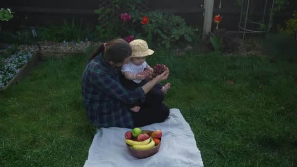 Χαρούμενη Νεαρή Χαρούμενη Μητέρα Που Κρατάει Μωρό Τρώγοντας Φρούτα Στο — Αρχείο Βίντεο