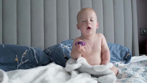 クローズアップハッピー遊び心眠い子供10ヶ月古い 新生児の男の子のカメラを見て後に白い柔らかいベッドの上でシャワー 赤ん坊は就寝前に時間をあくびをします 子供時代 幼児の概念 — ストック動画