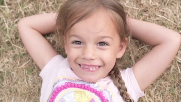 Mała Szczęśliwa Dziewczynka Sukience Kokardą Głowie Leżąca Zielonym Trawniku Parku — Wideo stockowe
