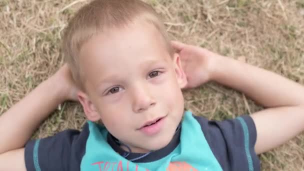 Mały Szczęśliwy Poważny Chłopiec Leżący Żółtym Trawniku Suchy Siano Trawy — Wideo stockowe