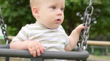 Komik, küçük, tombul kız, ablası, yeni doğmuş erkek kardeşi salıncakta sallıyor. Bebek oyun parkında oynuyor. Çocuk Eğlencesi, Çocukluk, Çocuk Geliştirme, Mutlu Aile Kavramı.