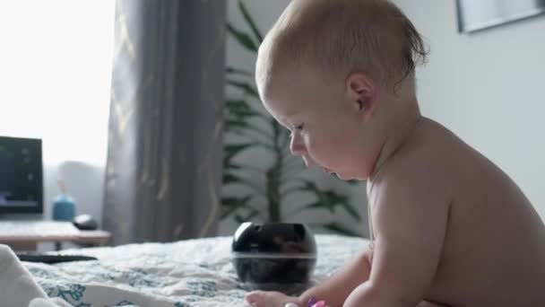 개월된 아기가 가까이 장난기있게 있습니다 스마트폰을 가지고 태어난 침대에 장비도 — 비디오