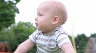 Mutlu aile piknik yapıyor. Küçük bebek yeşil çimlerde sürünüyor. Park yazında. Green Park 'ta oynayan kardeşler. Oyun salonunda aile eğlencesi ve neşe. Aktif oğul tarlada yalınayak sürünüyor..