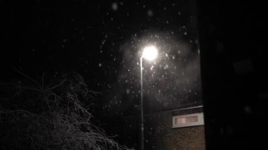 Birleşik Krallık 'taki ilk kar yağışı örtüsü kara arka planda. Gece Yolu 'ndaki Lambanın Işığında Düşen Kar Taneleri Kış, Yavaşça Düşen Kar Etkisi. Hava Durumu, Anomali, Acil Durum Konsepti.